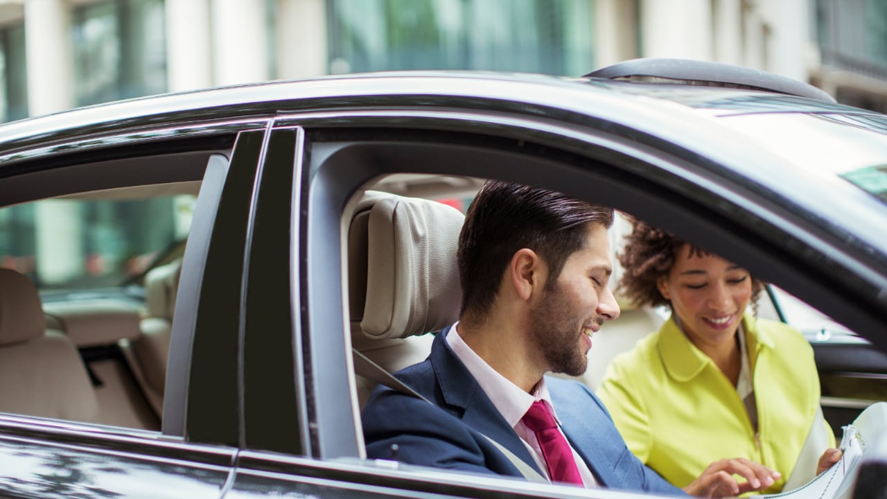 Homme dans femme à l'avant d'une voiture se parlant.