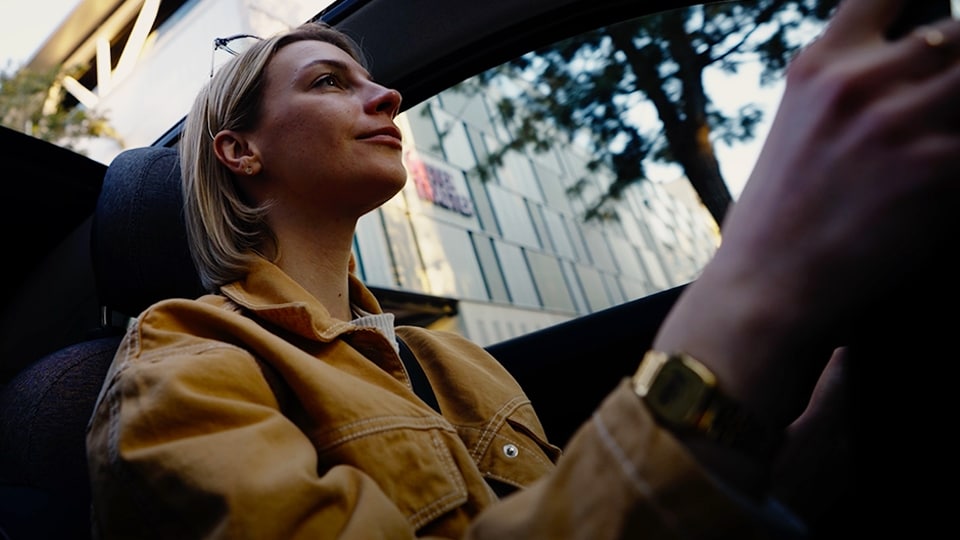 Femme en veste jaune conduisant une voiture.