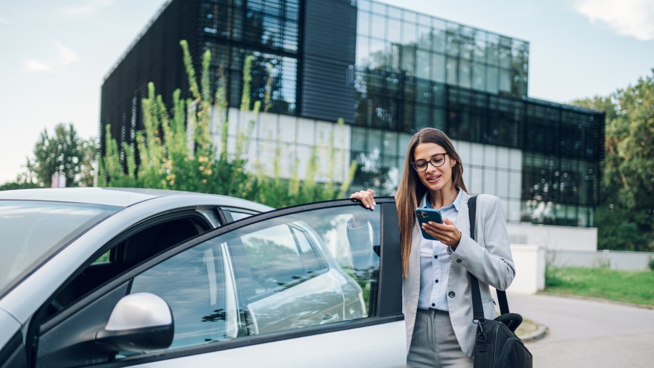 Femme sur son téléphone montant dans une voiture.