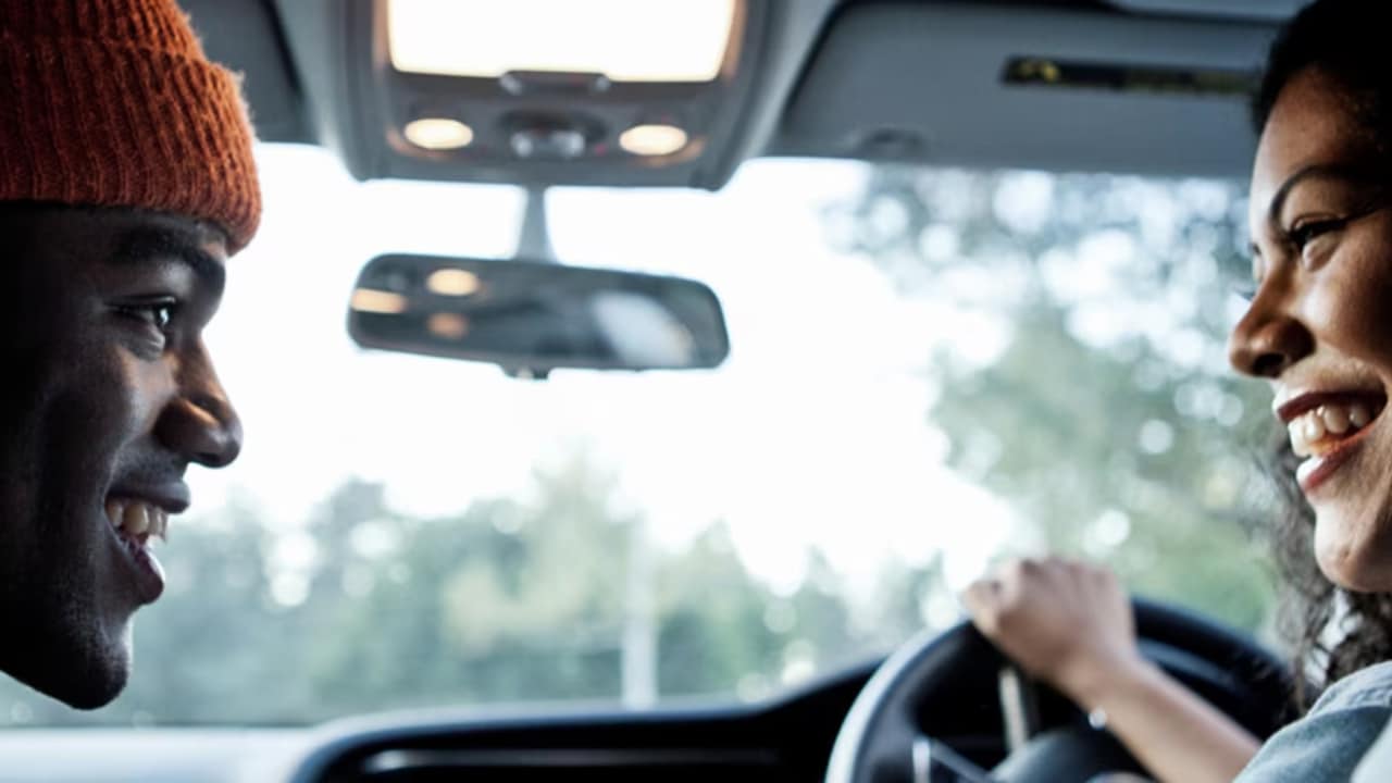 Gros plan d'un homme et d'une femme qui parlent dans une voiture.